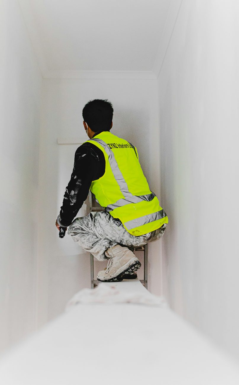 A worker skim-coating and prepping a ceiling before painting